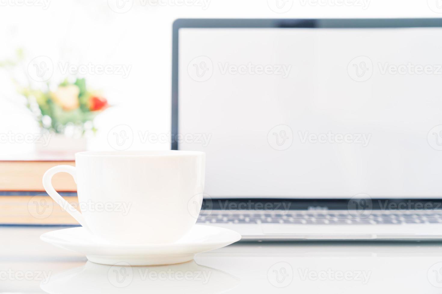 Cup of coffee with blank screen laptop computer on deck photo