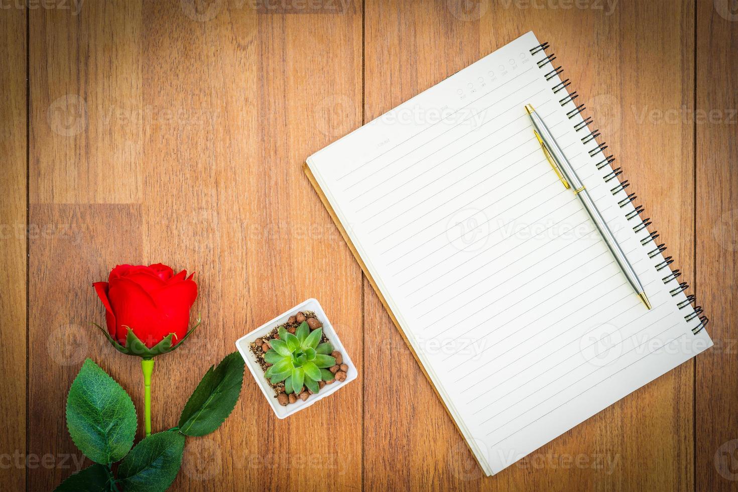 rosas rojas en la mesa de madera y el bloc de notas foto