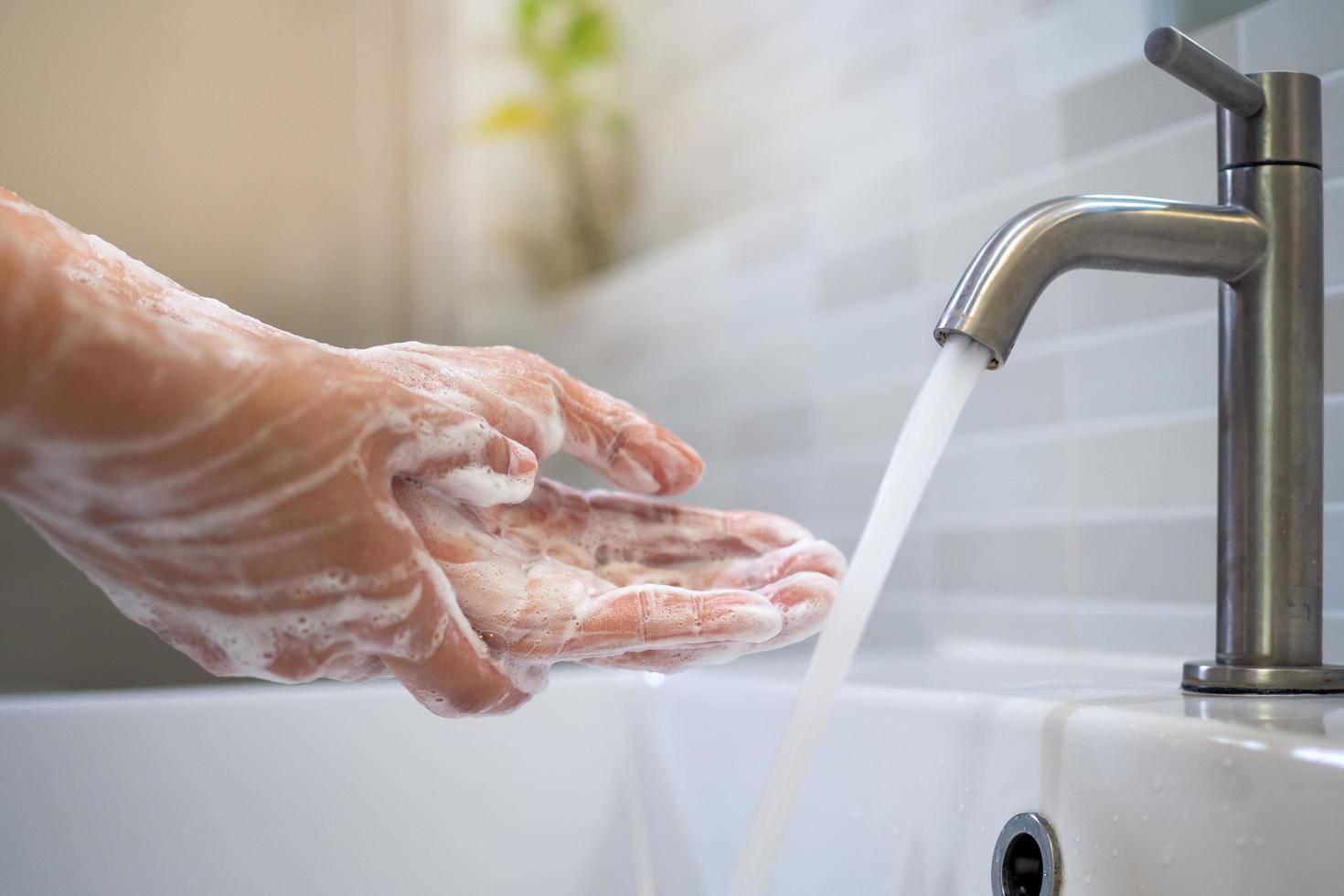 lavarse las manos con jabón y lavarse con agua corriente. primer plano de mujeres frotando jabón de manos con lavabo. el concepto de higiene de manos y días de lavado de manos en todo el mundo. reducir la infección covit-19 foto