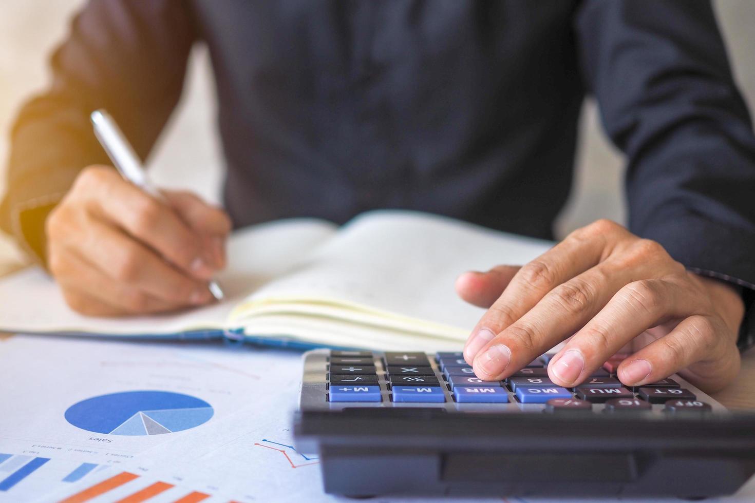 Businessmen use calculators to calculate numbers and view statistical data within the office. Financial and investment accounting concepts photo