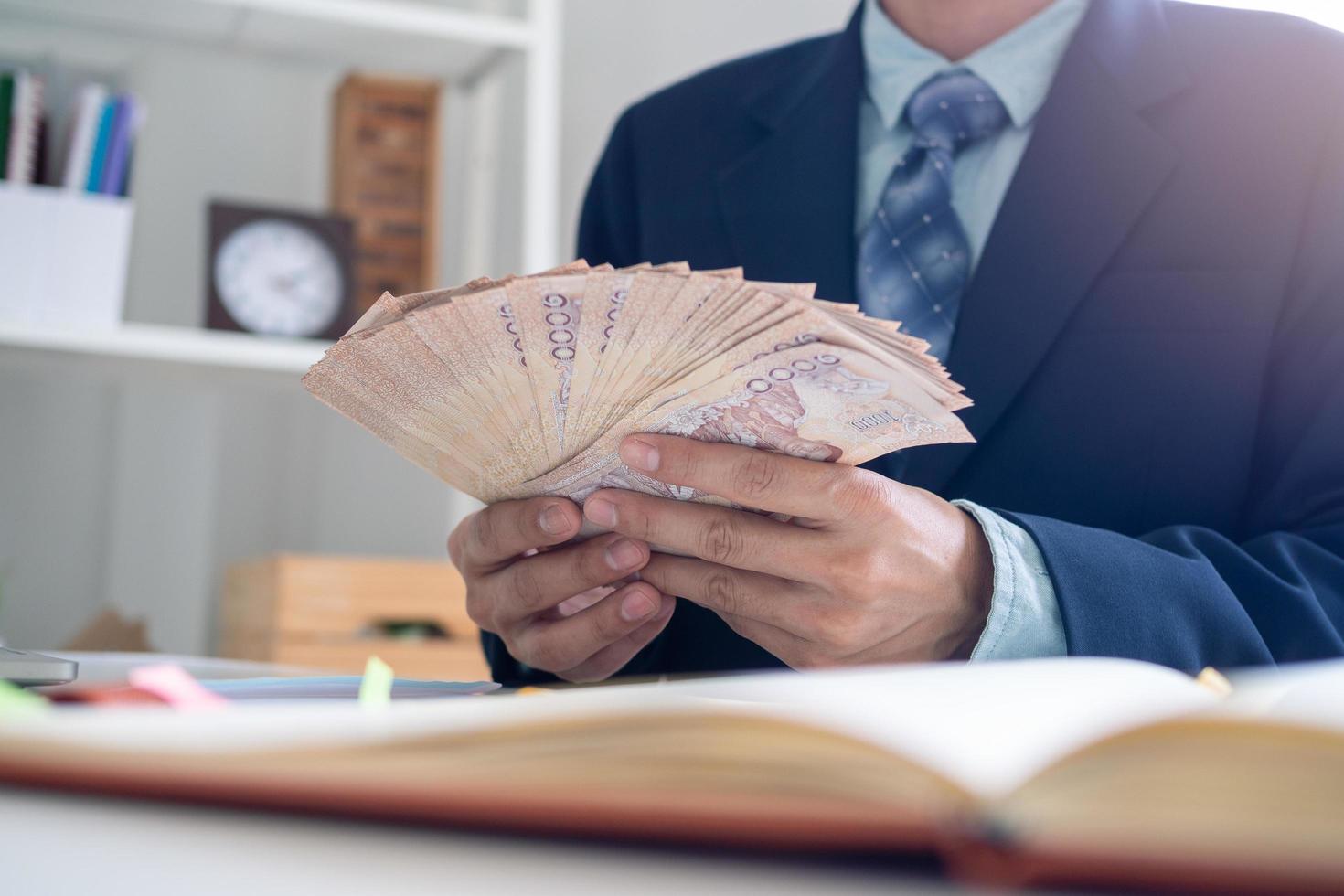 Businessmen sit counting money in baht in the office, preparing to distribute salaries and bonuses or contributions to employees in the company. Employee Assistance Fund for Thai people photo