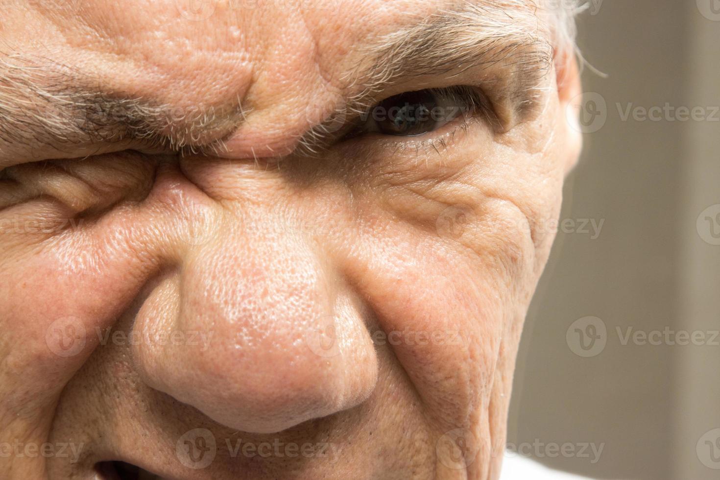 primer plano de un hombre mayor con un ojo cerrado entrecerrando los ojos foto