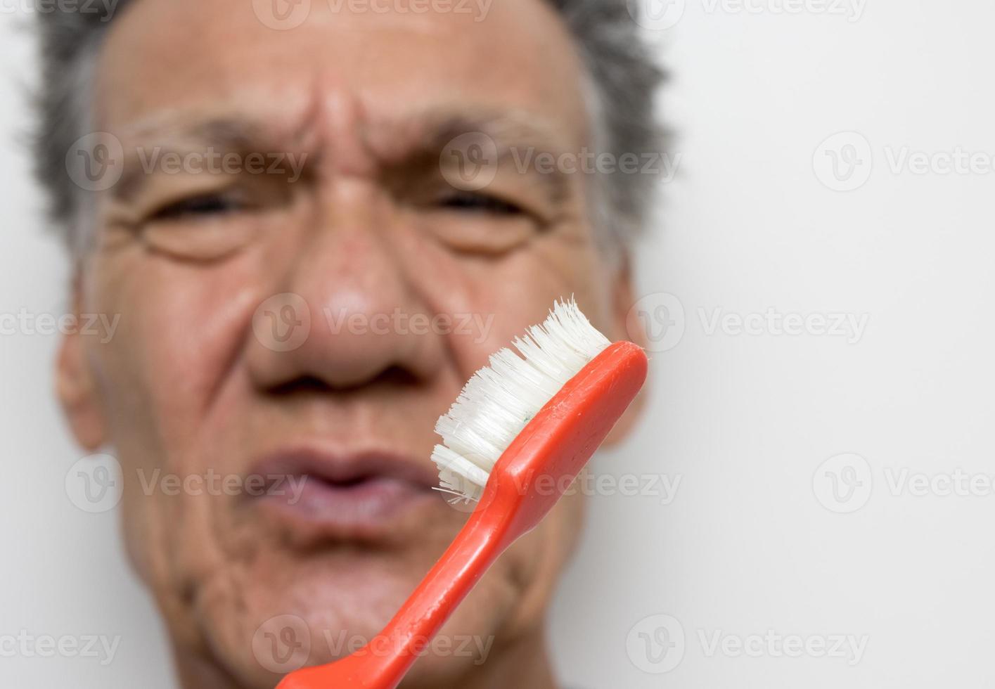 anciano mirando su viejo cepillo de dientes desgastado foto