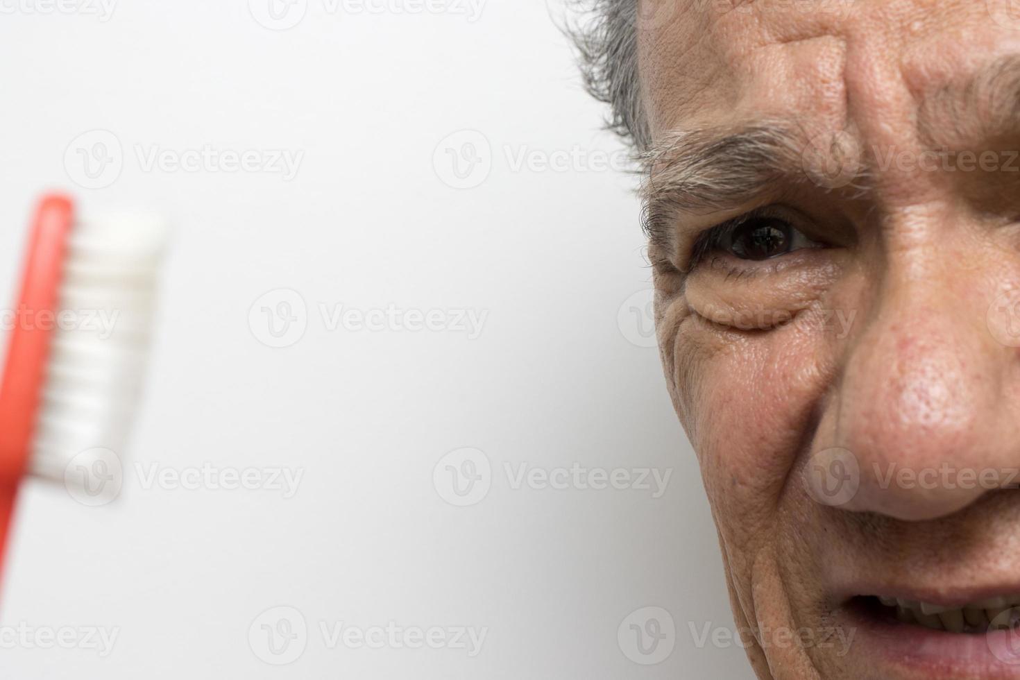 Senior man looking at his old worn our toothbrush photo