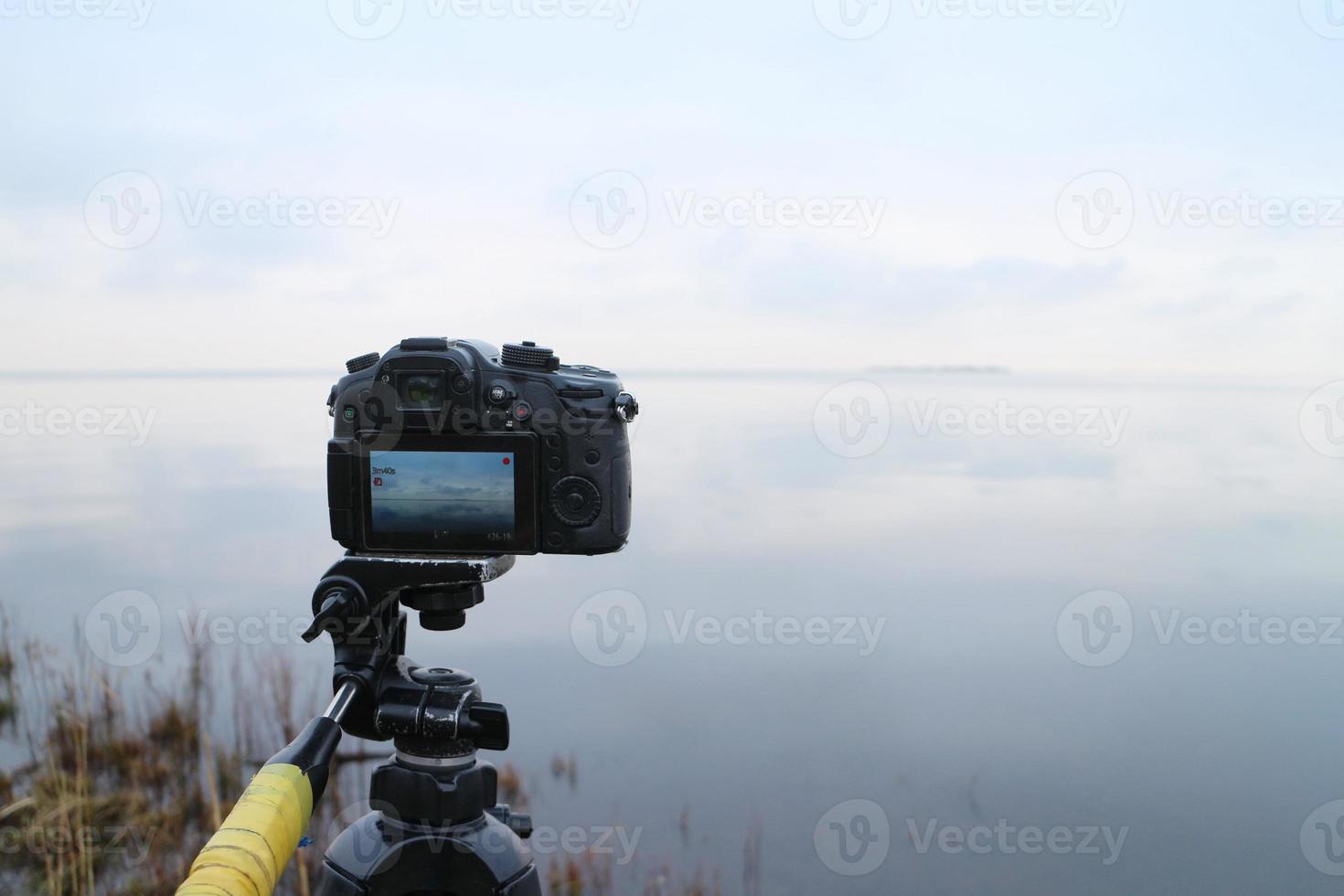 cámara de fotos en un trípode captura un hermoso paisaje marino, concepto de videografía