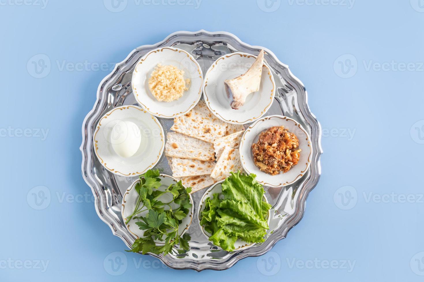 a silver plate with traditional Jewish treats for Passover. baked egg, lettuce, horseradish, bone, nuts and matzah. a symbol of the Jewish Passover. photo