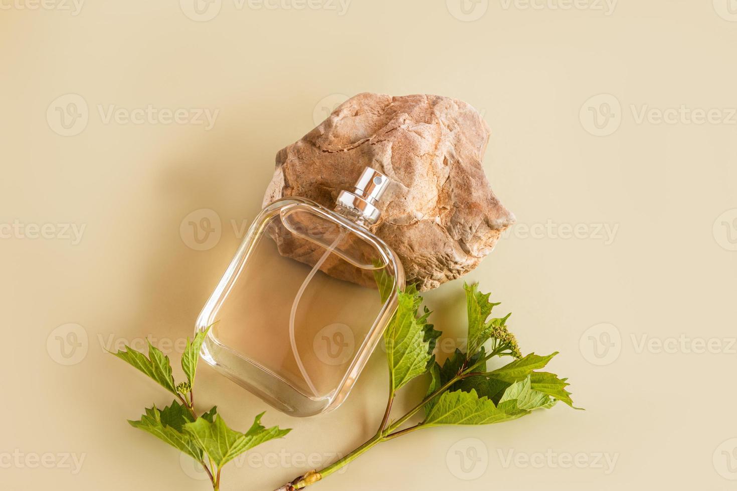 A beautiful bottle of perfume or cosmetic spray lies on a natural stone and a beige background. top view. unnamed bottle. product presentation. photo