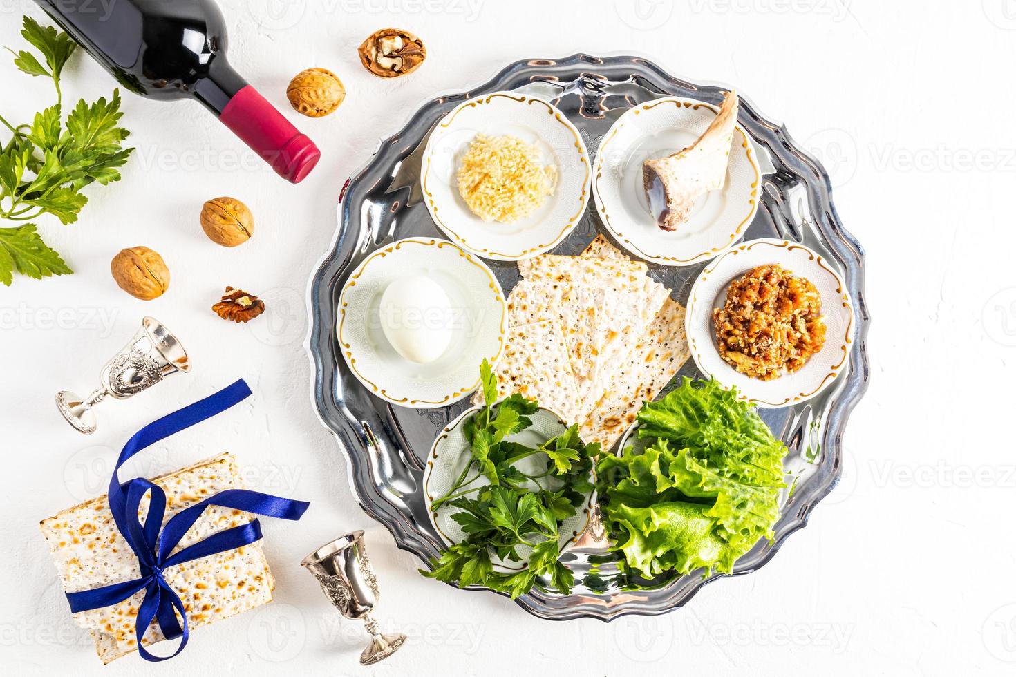 a silver plate with traditional Jewish treats for Passover. baked egg, lettuce, horseradish, bone, nuts and matzah. a symbol of the Jewish Passover. photo