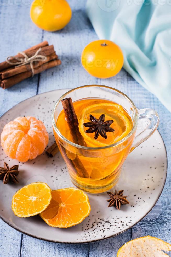 té de mandarina fresca con canela en una taza sobre la mesa. bebida vitamínica vista vertical foto