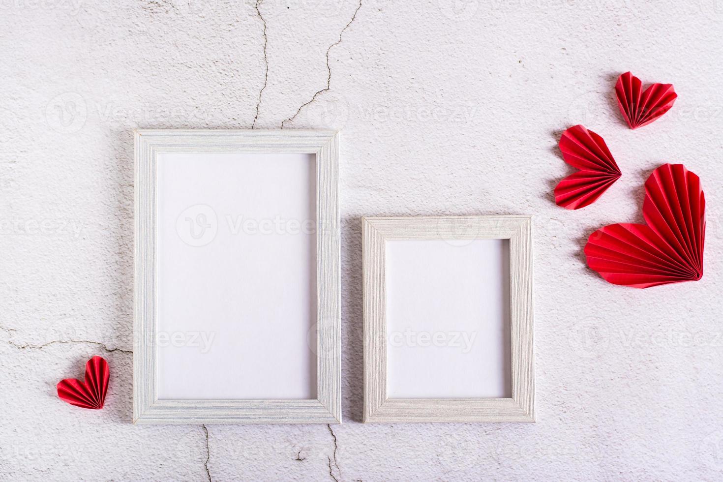 Paper red do-it-yourself hearts around empty photo frames on a concrete background. Valentine's Day.