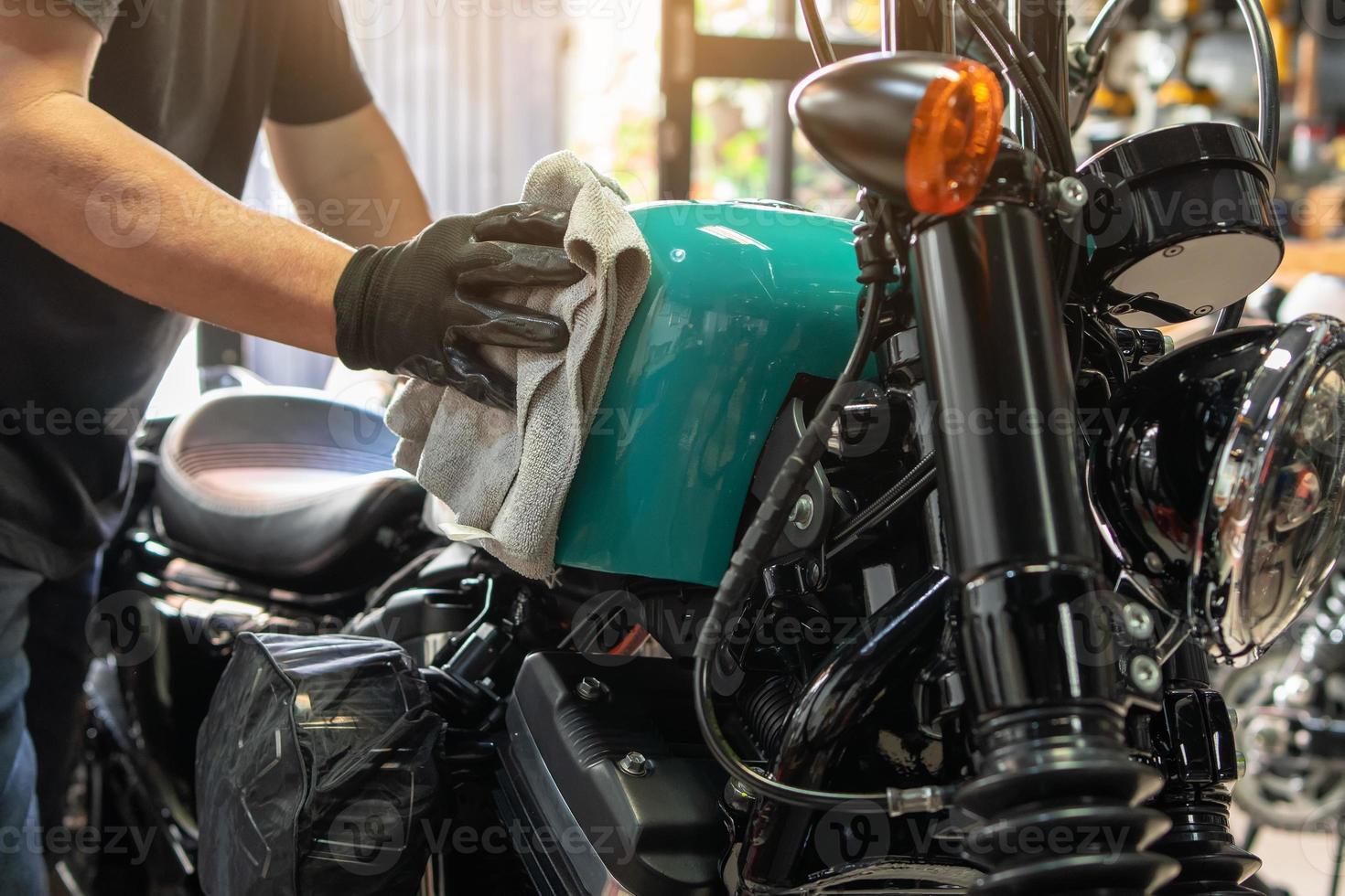 motociclista limpiando motocicletas, puliendo y recubriendo cera en el tanque de combustible en el garaje. concepto de reparación y mantenimiento de motocicletas. foto