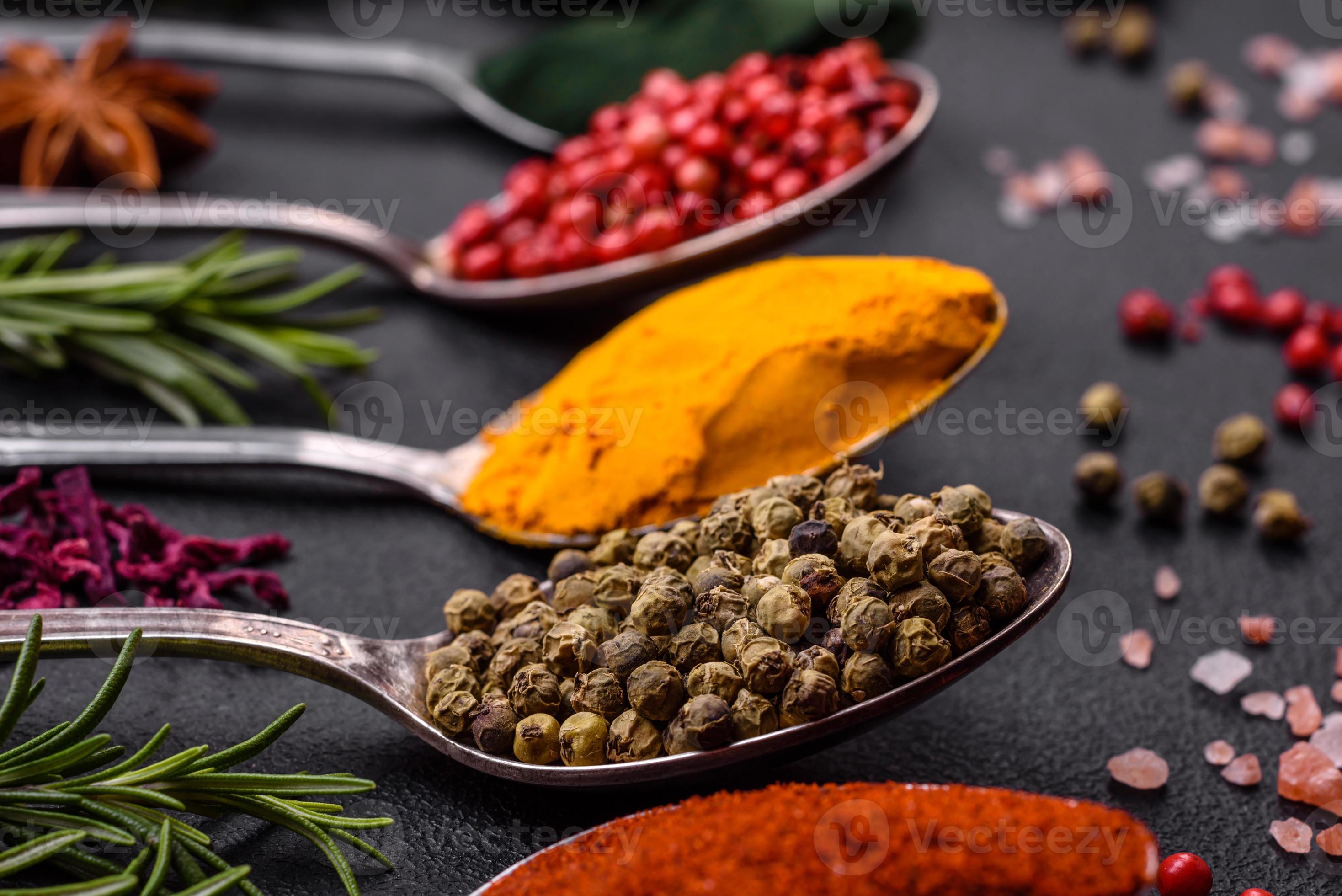 Variation of spices in metal spoons paprika, turmeric, cardamom, a ...