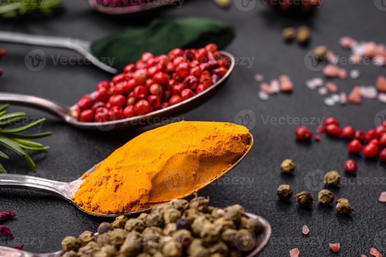 Variation of spices in metal spoons paprika, turmeric, cardamom, a ...