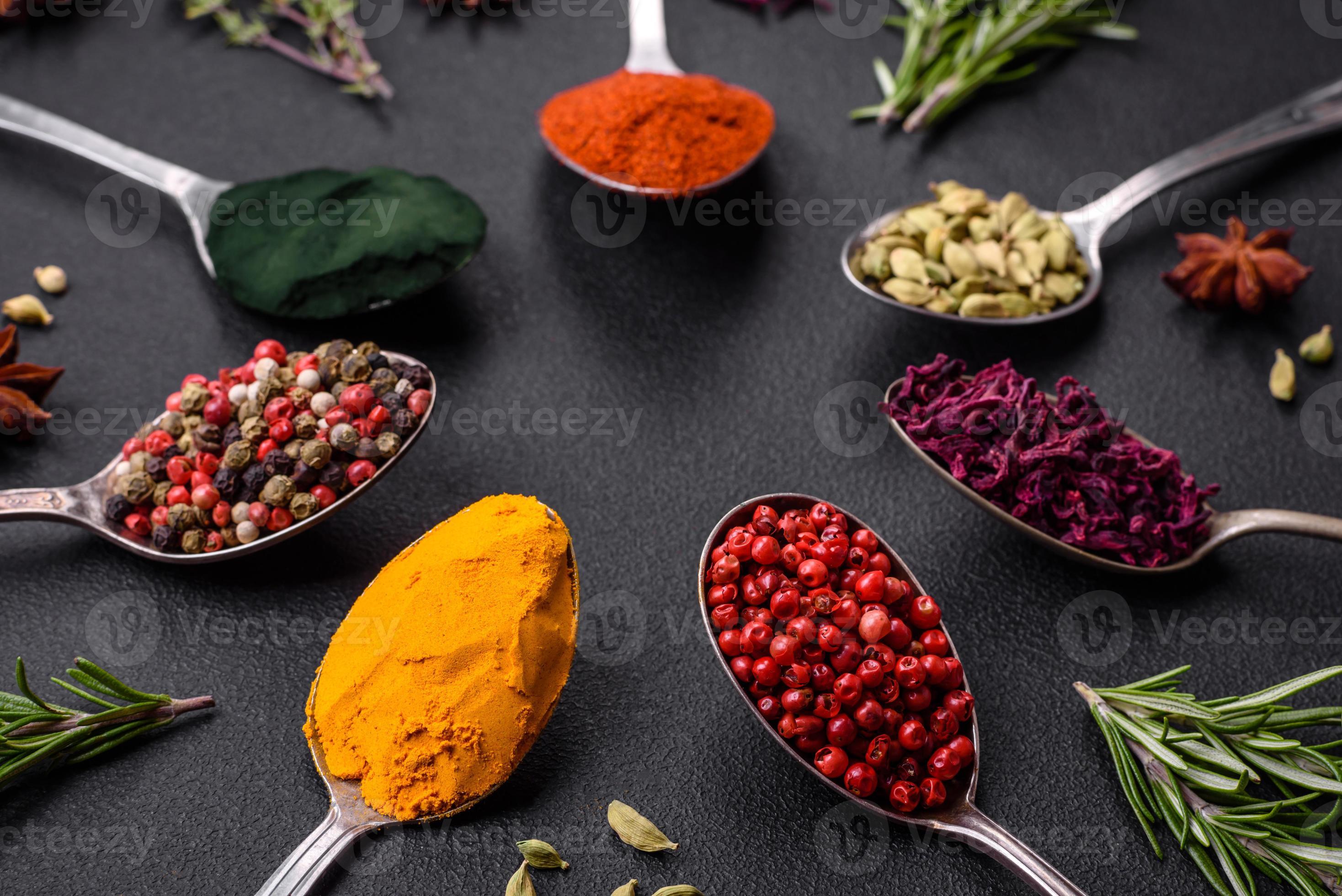 Variation of spices in metal spoons paprika, turmeric, cardamom, a ...