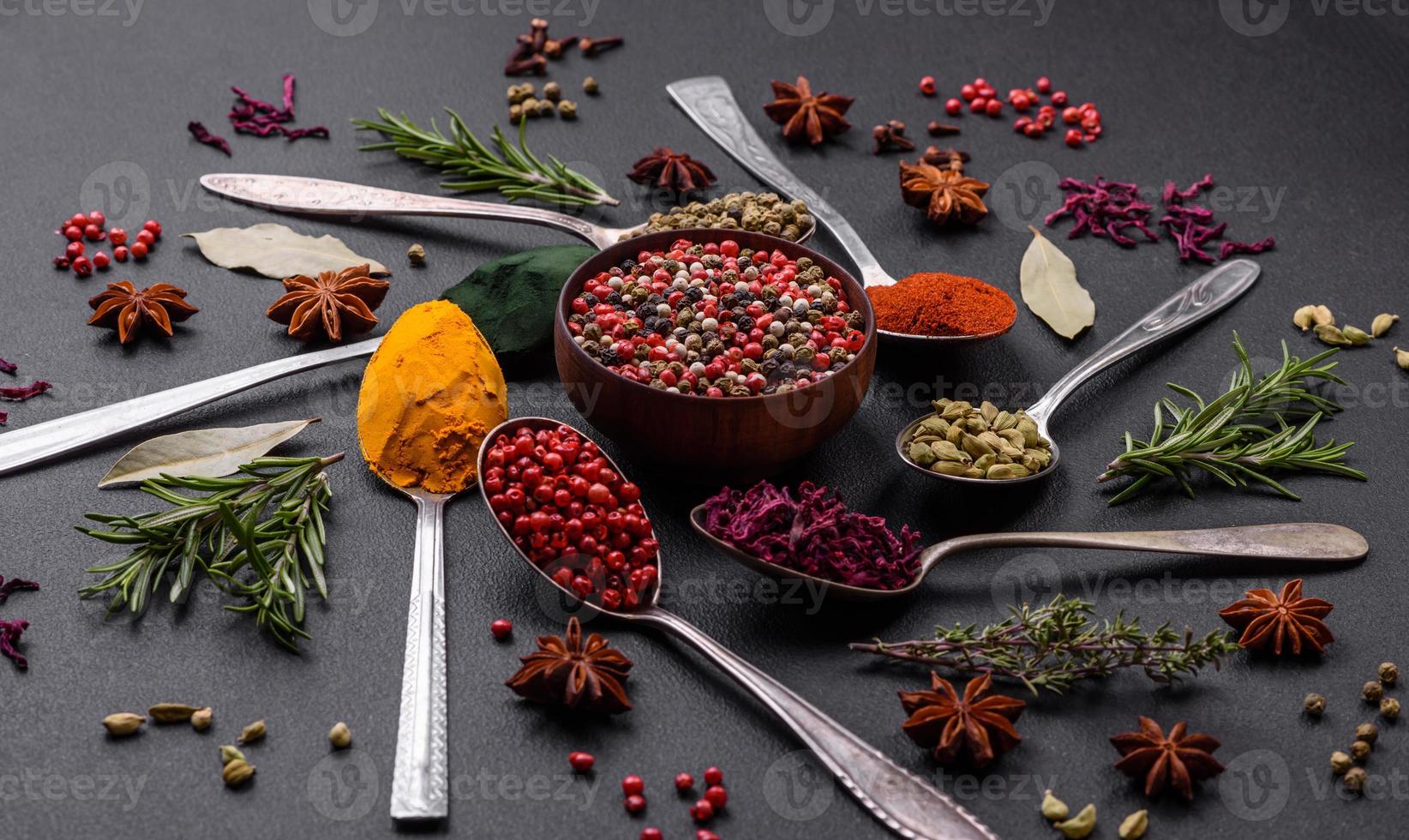 Variation of spices in metal spoons paprika, turmeric, cardamom, a mixture of allspice, thyme and rosemary photo