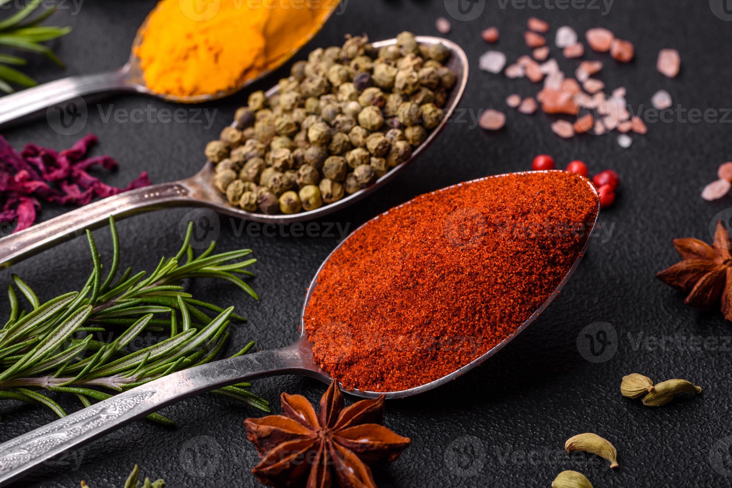 Variation of spices in metal spoons paprika, turmeric, cardamom, a ...