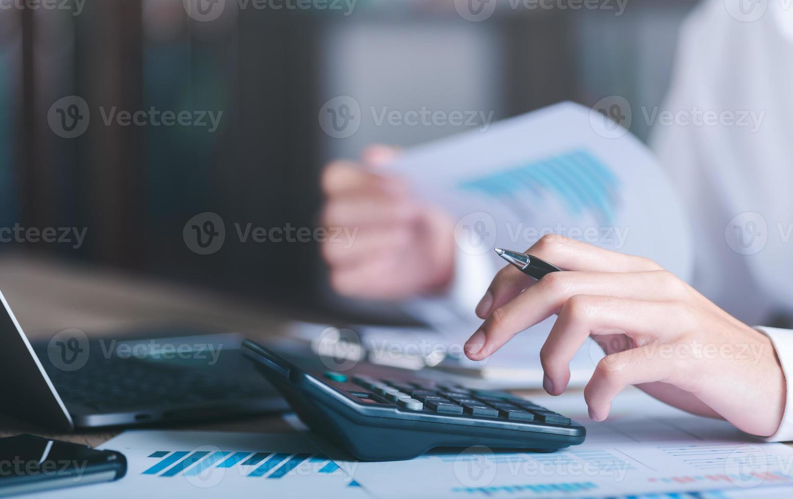 Businessman calculating figures in company financial documents with a calculator,analysis of company financial data,Planning to assess and review budgets,concept of finance and investment photo