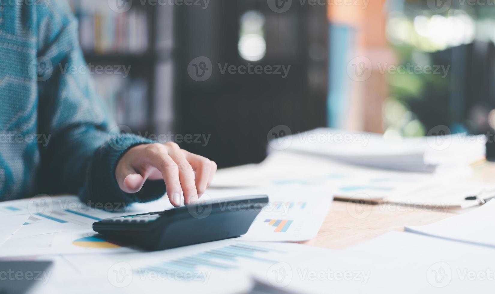 Businessman calculating figures in company financial documents with a calculator,analysis of company financial data,Planning to assess and review budgets,concept of finance and investment photo