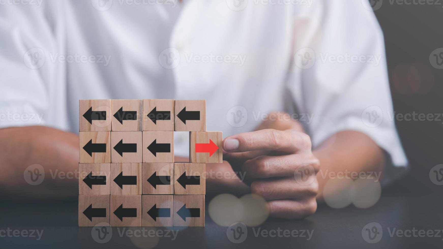 Young businessman selecting wooden blocks with red arrows and different directions Leadership concept and growth of business competition Changing Strategic Vision for Chances of Success photo