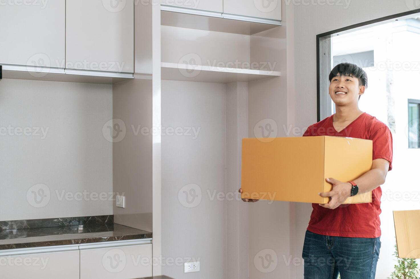 un joven lleva un paquete grande y entra en una casa nueva foto