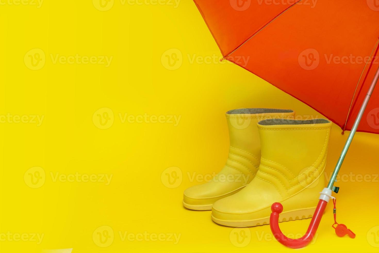 yellow boots under a red umbrella on a yellow background with copy space. photo