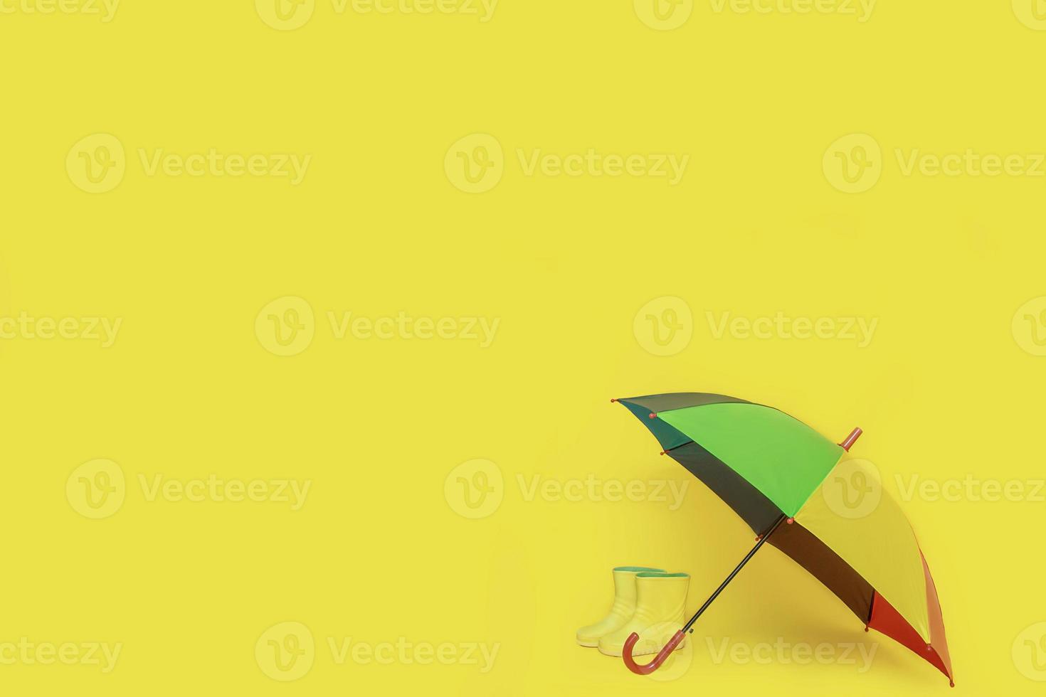 children's boots under a multi-colored umbrella with copy space photo