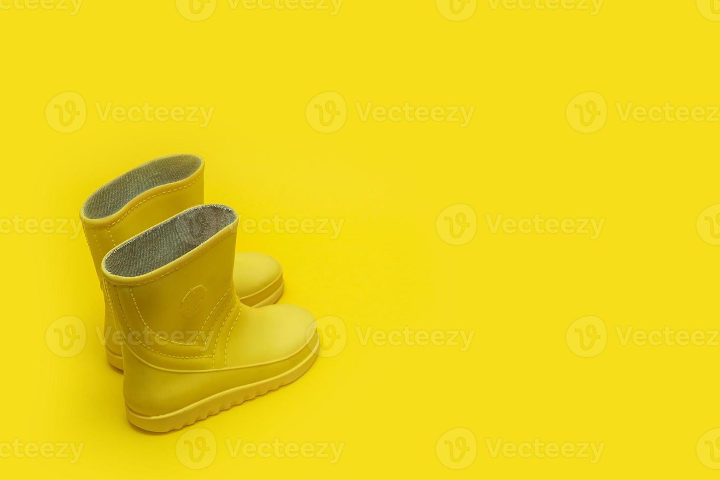yellow children's rubber boots on a yellow background with copy space photo