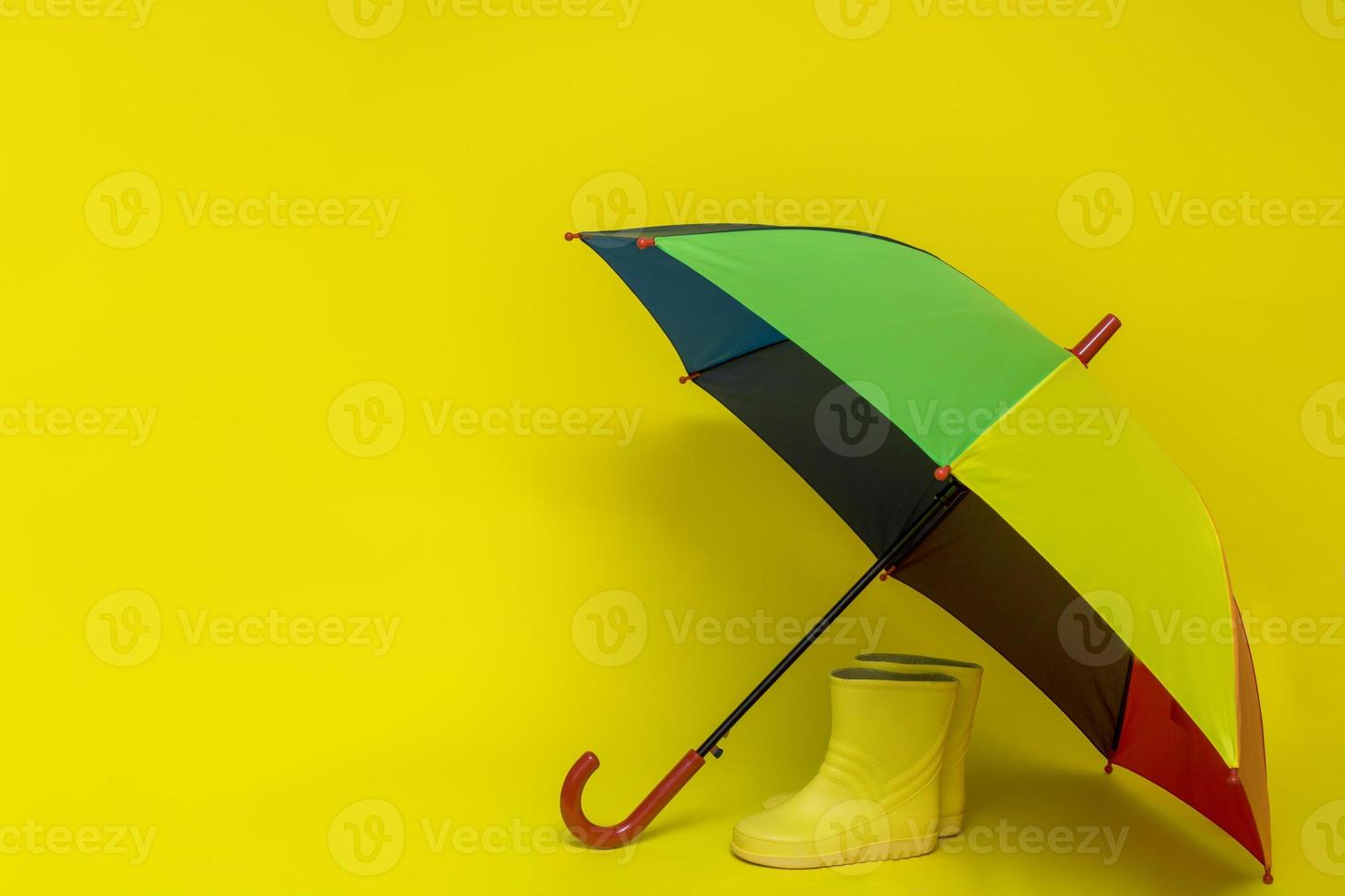 children's boots under a multi-colored umbrella with copy space photo