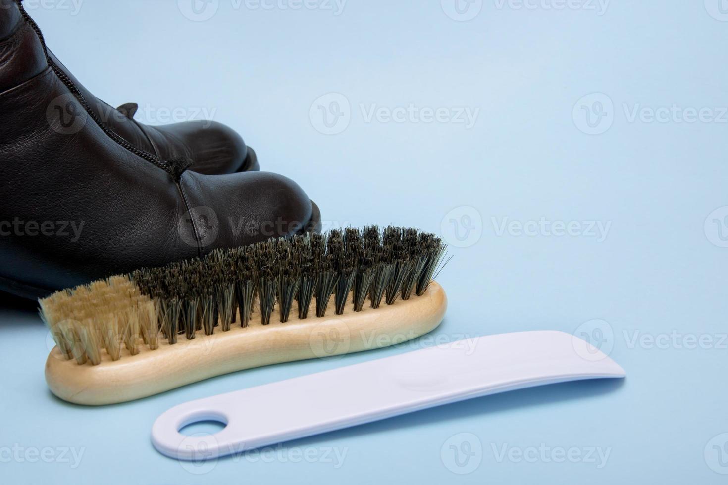 black boots with a brush and a shoe horn on a blue background photo