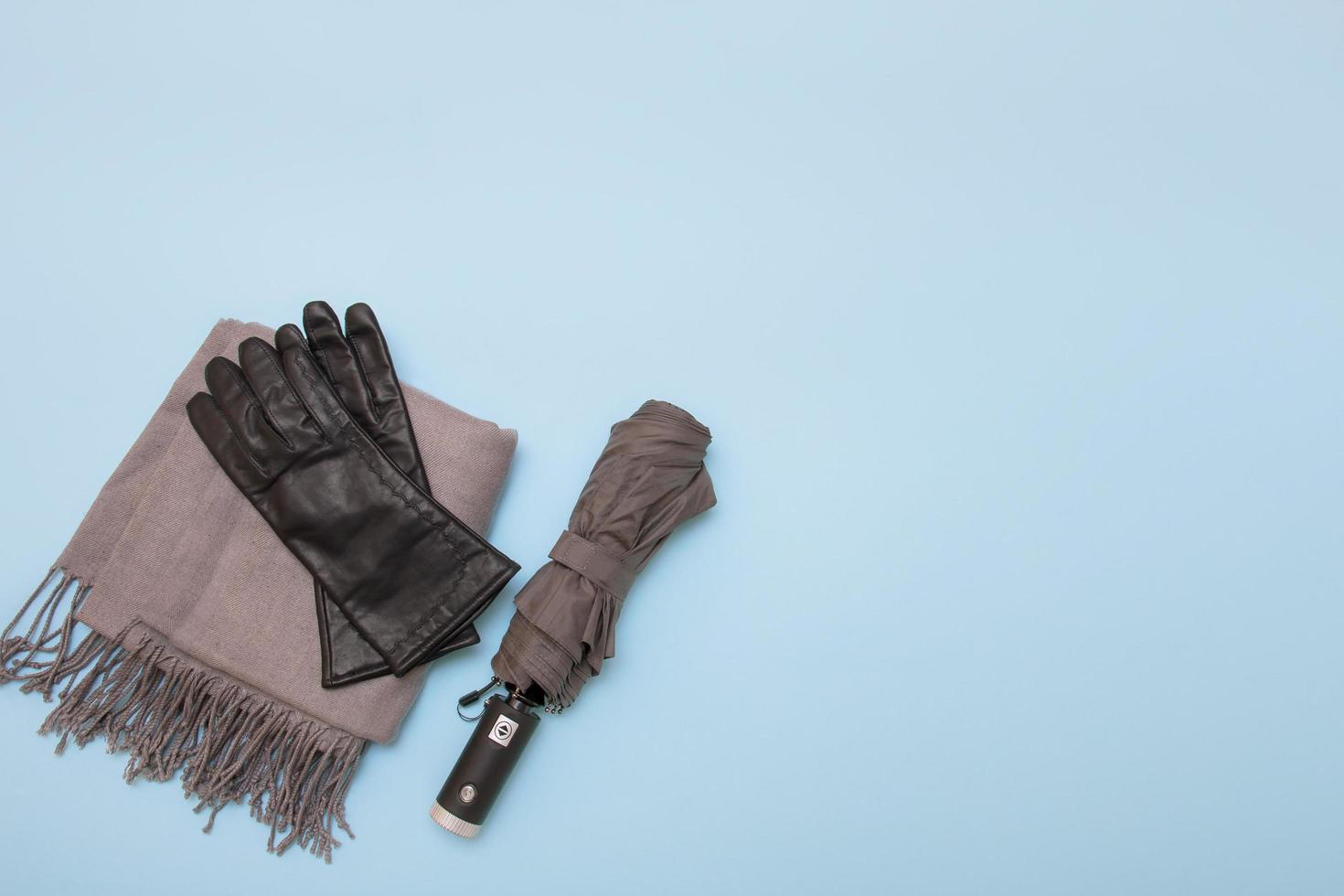 bufanda gris y paraguas gris con guantes sobre un fondo azul con espacio para copiar foto