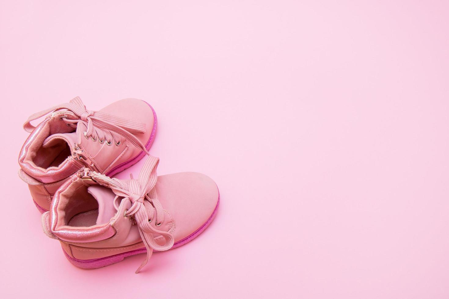 children's pink shoes on a pink background with copy space photo