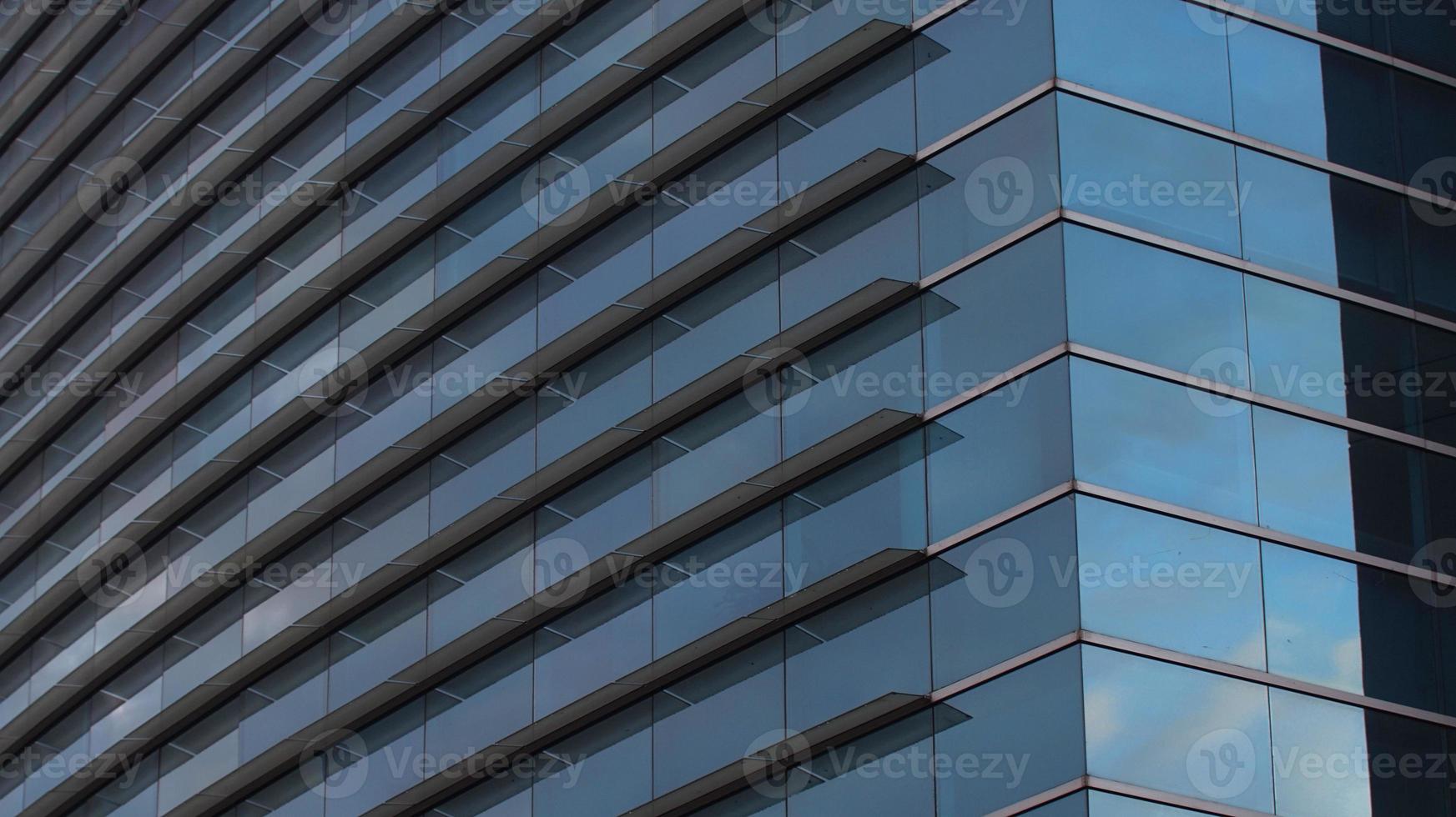 Approach to the glass windows reflecting a blue sky of a modern building. Abstract background photo