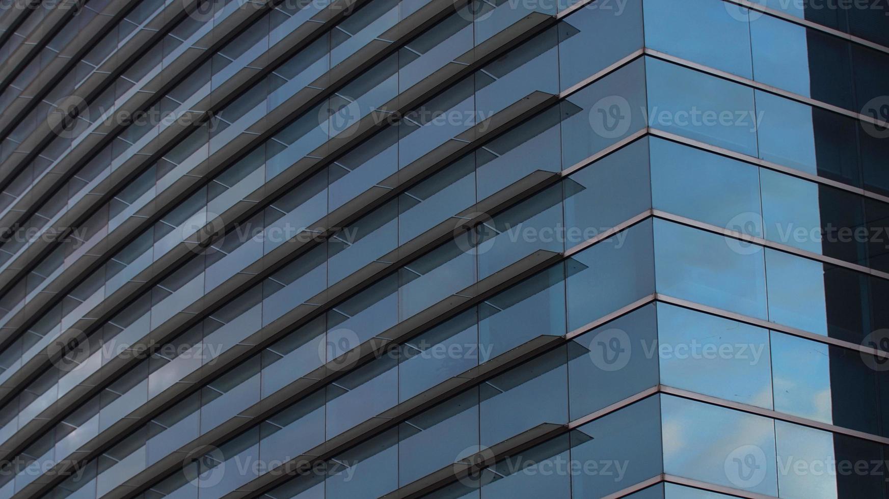 acercarse a las ventanas de cristal que reflejan un cielo azul de un edificio moderno. fondo abstracto foto