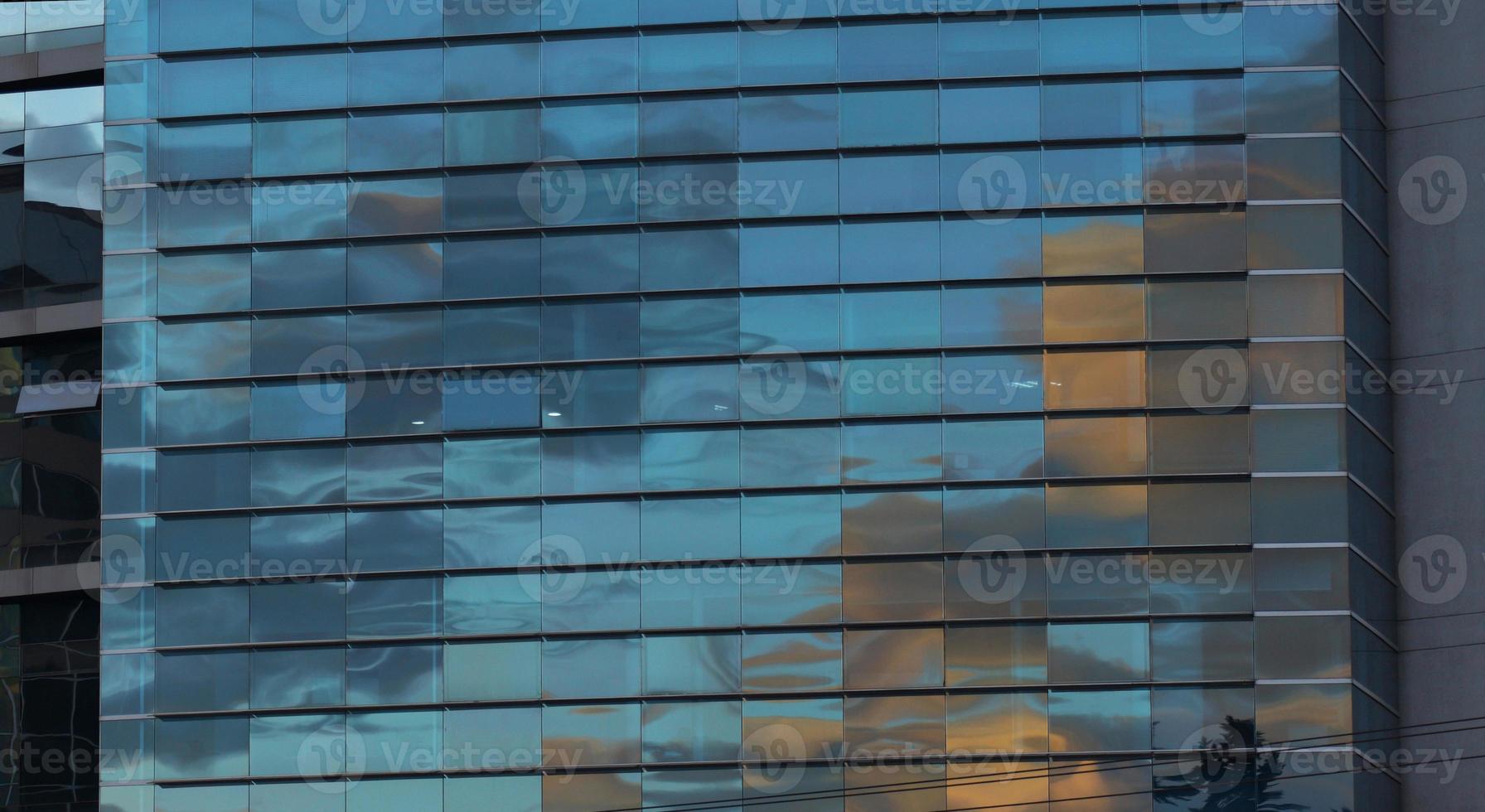 Approach to the glass windows reflecting a blue sky of a modern building. Abstract background photo