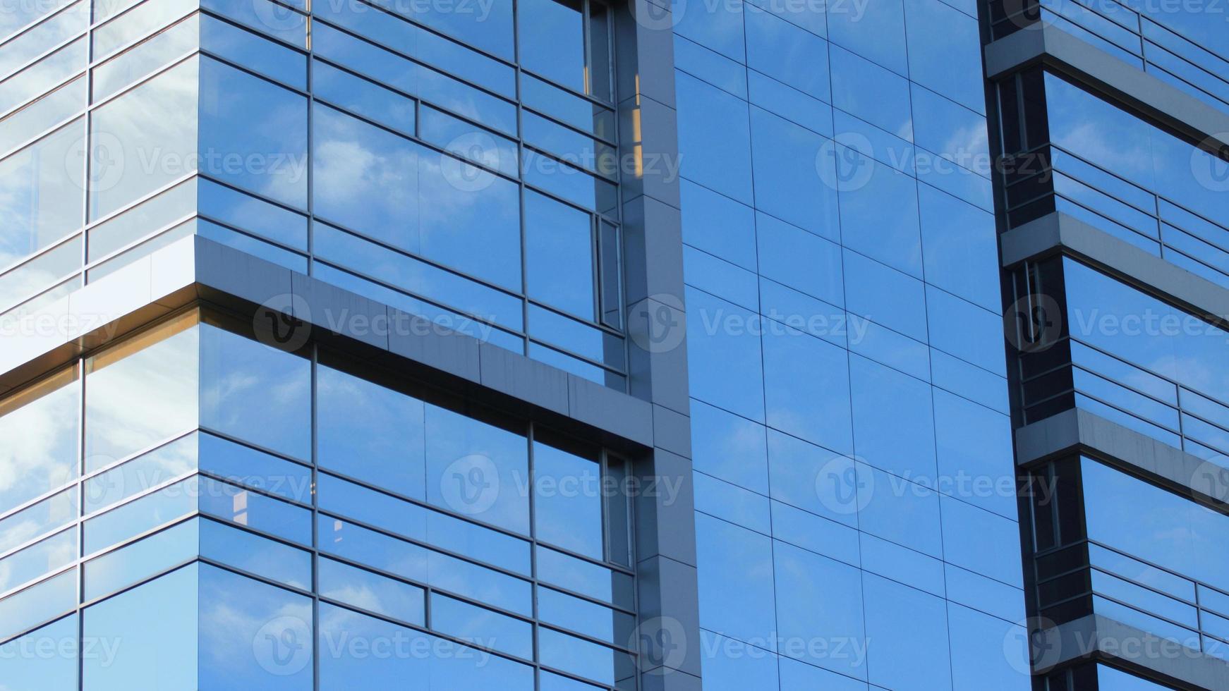 Approach to the glass windows reflecting a blue sky of a modern building. Abstract background photo