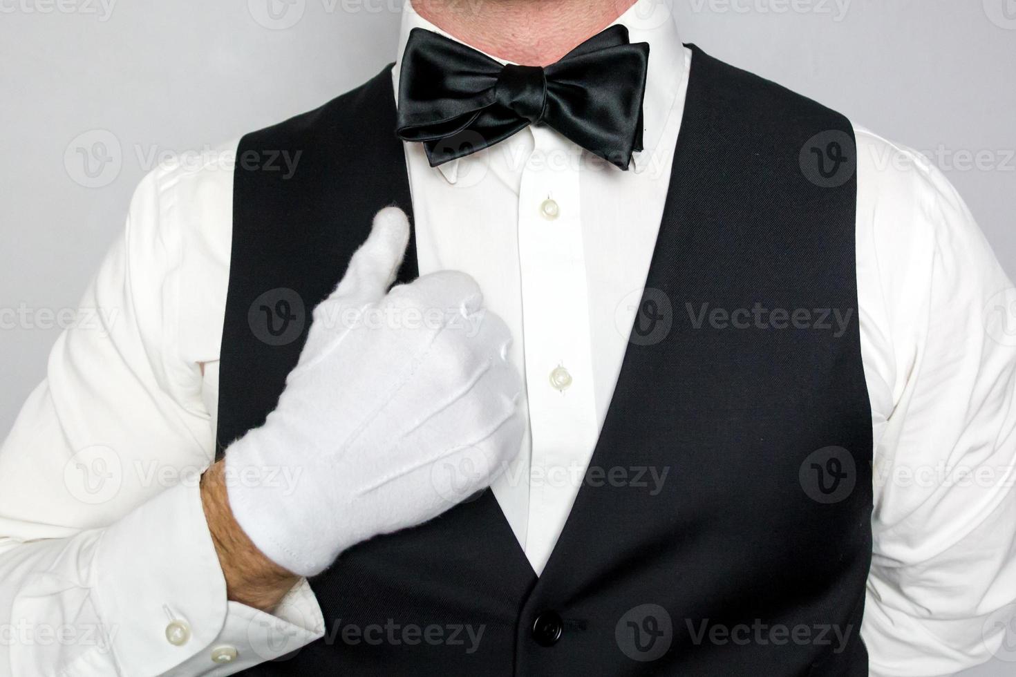 Close Up Image of Waiter or Butler in White Gloves and Black Bow Tie and Vest on a White Background. Concept of Service Industry and Professional Hospitality. photo