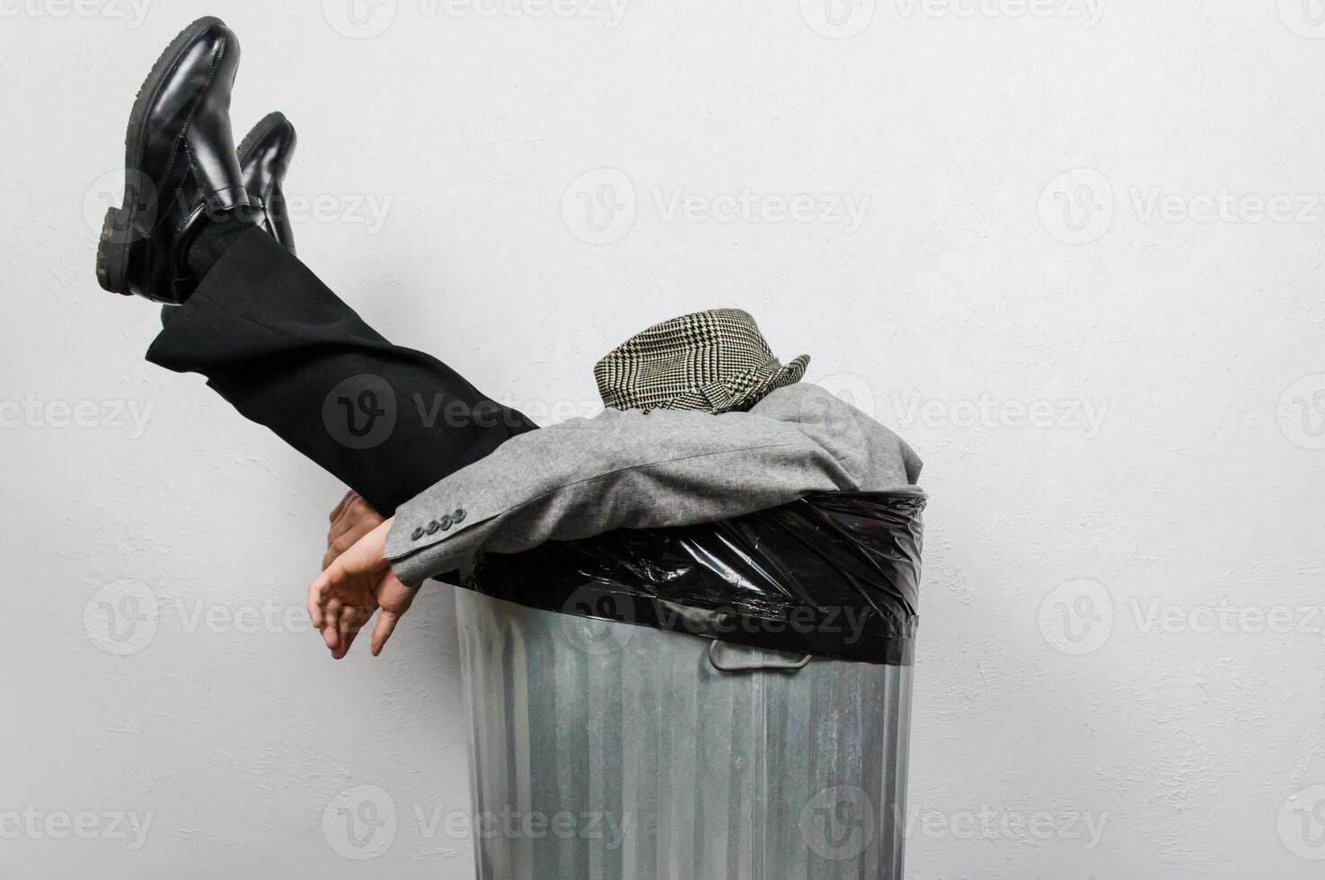 Portrait of Businessman in Suit and Fedora Hat Sitting in Trash Can. Man Thrown Away by