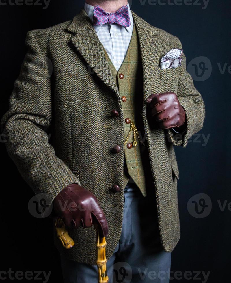 Portrait of Man in Tweed Suit and Leather Gloves Holding Umbrella on Black Background. Classic and Eccentric English Gentleman. photo