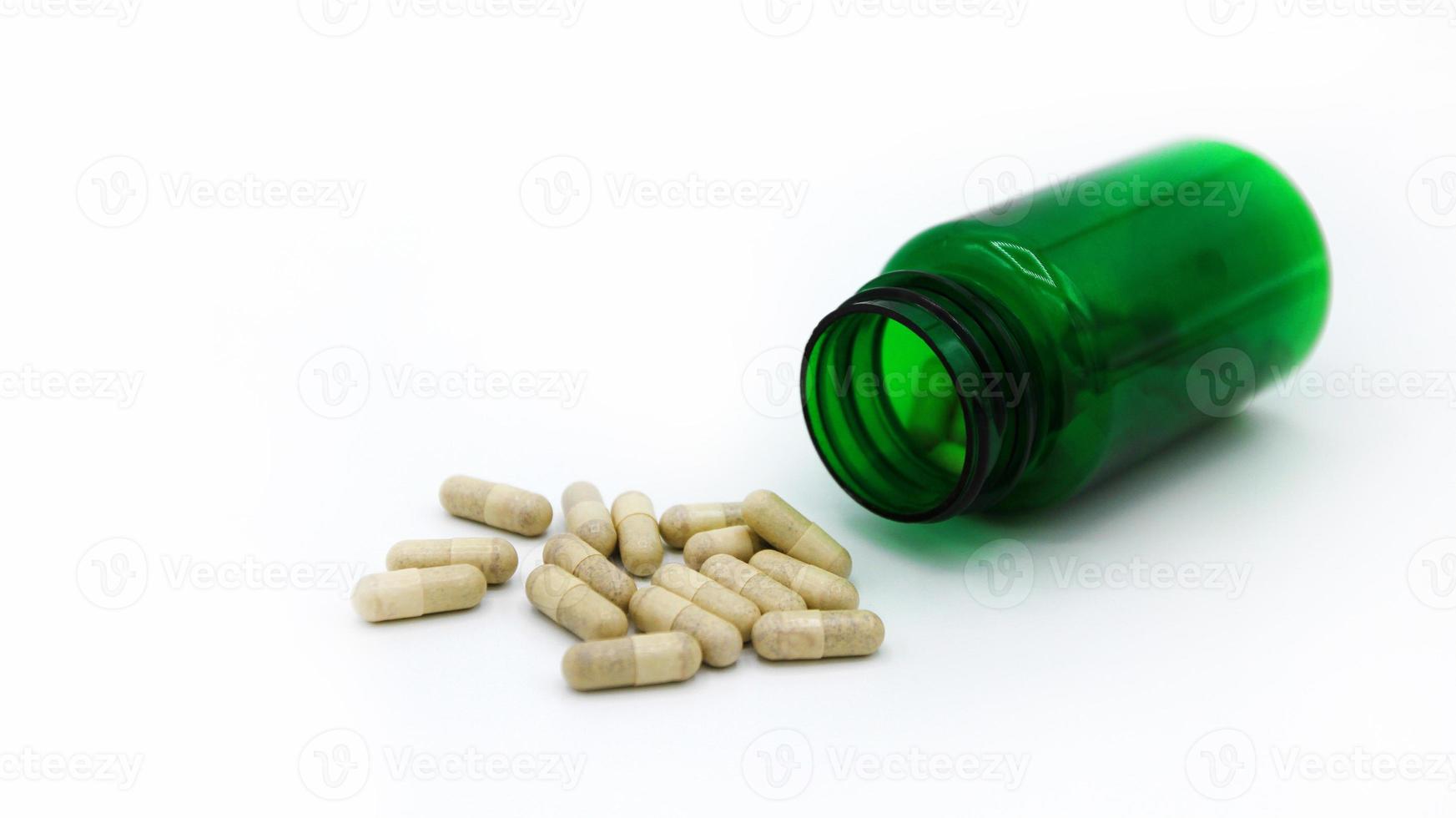 White pills spilling or pour out of green pill bottle isolated on white background with copy space for add text. Healthy, herb, container object and Medicine. Food supplement for cure or repair health photo