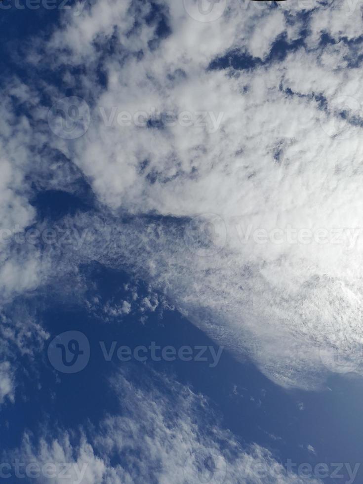 White clouds in the blue sky. Beautiful bright blue background. Light cloudy, good weather. Curly clouds on a sunny day. photo