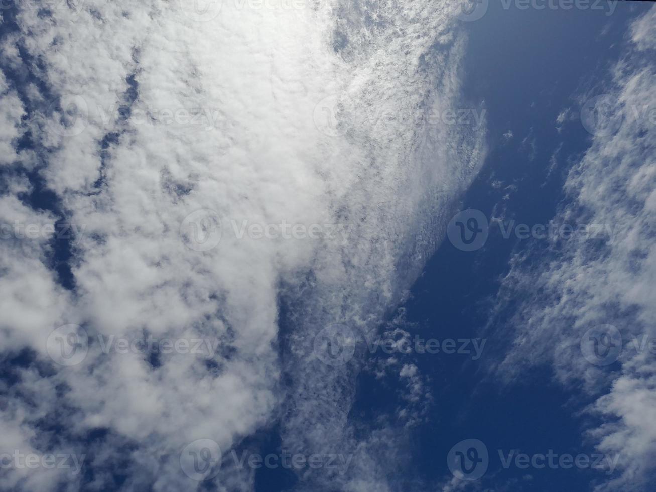 White clouds in the blue sky. Beautiful bright blue background. Light cloudy, good weather. Curly clouds on a sunny day. photo