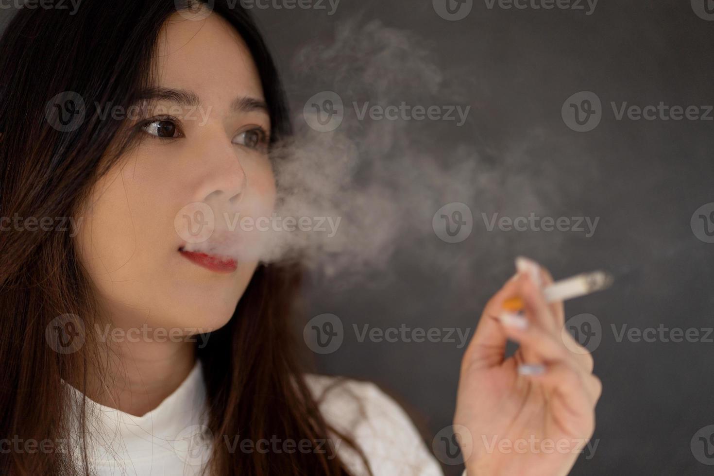 mujer asiática fumando con humo de cigarrillo foto