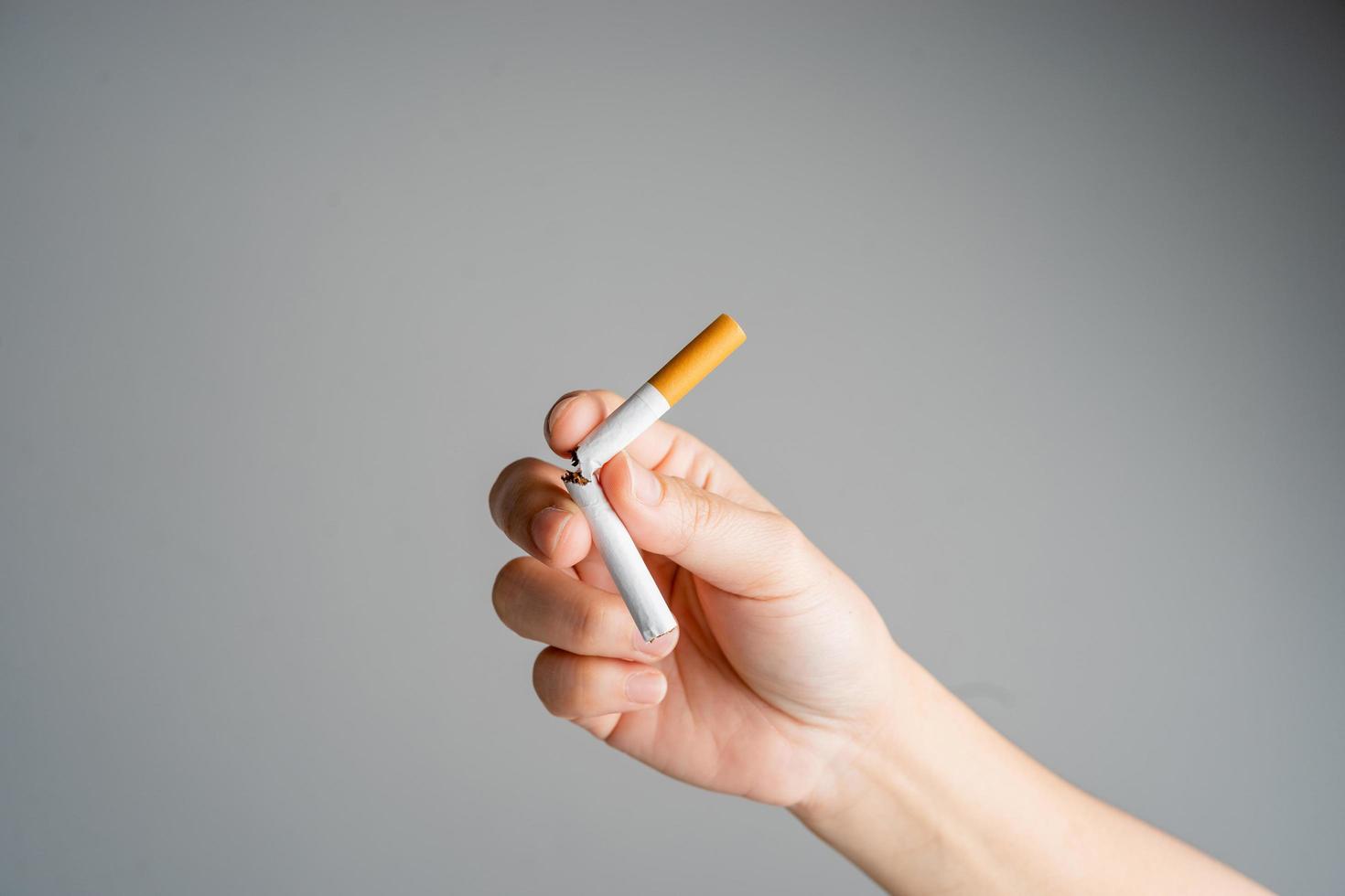 Stop smoking, quit smoking or no smoking cigarettes. Woman holding broken cigarette in hands. Woman refusing cigarettes and lung health concept. photo