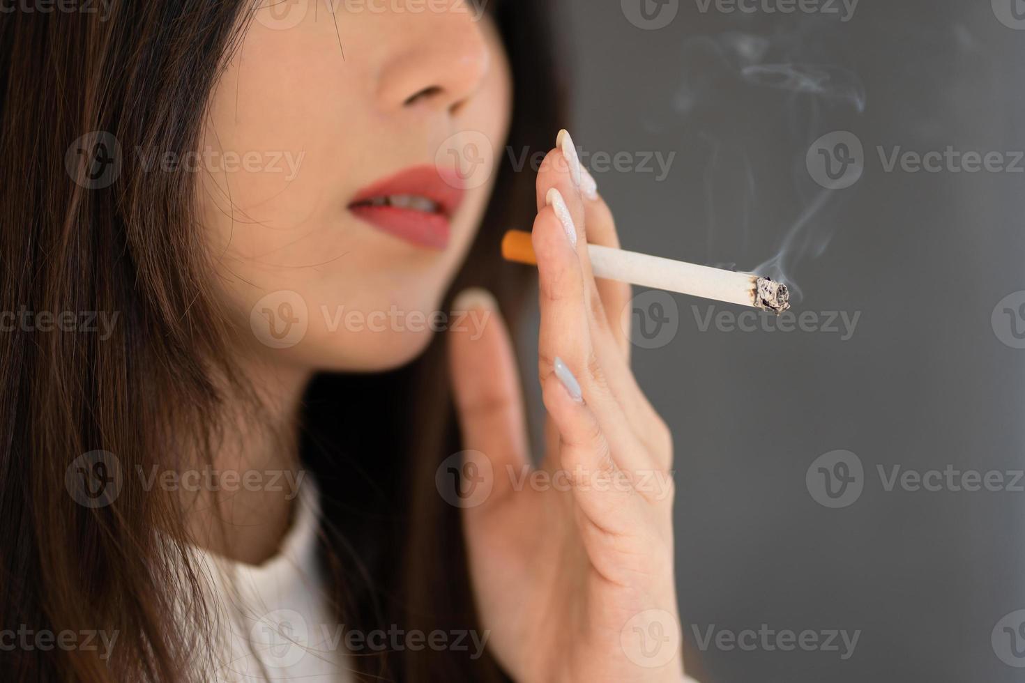 Close up hand holding cigarette, Asian woman smoking outdoors. photo