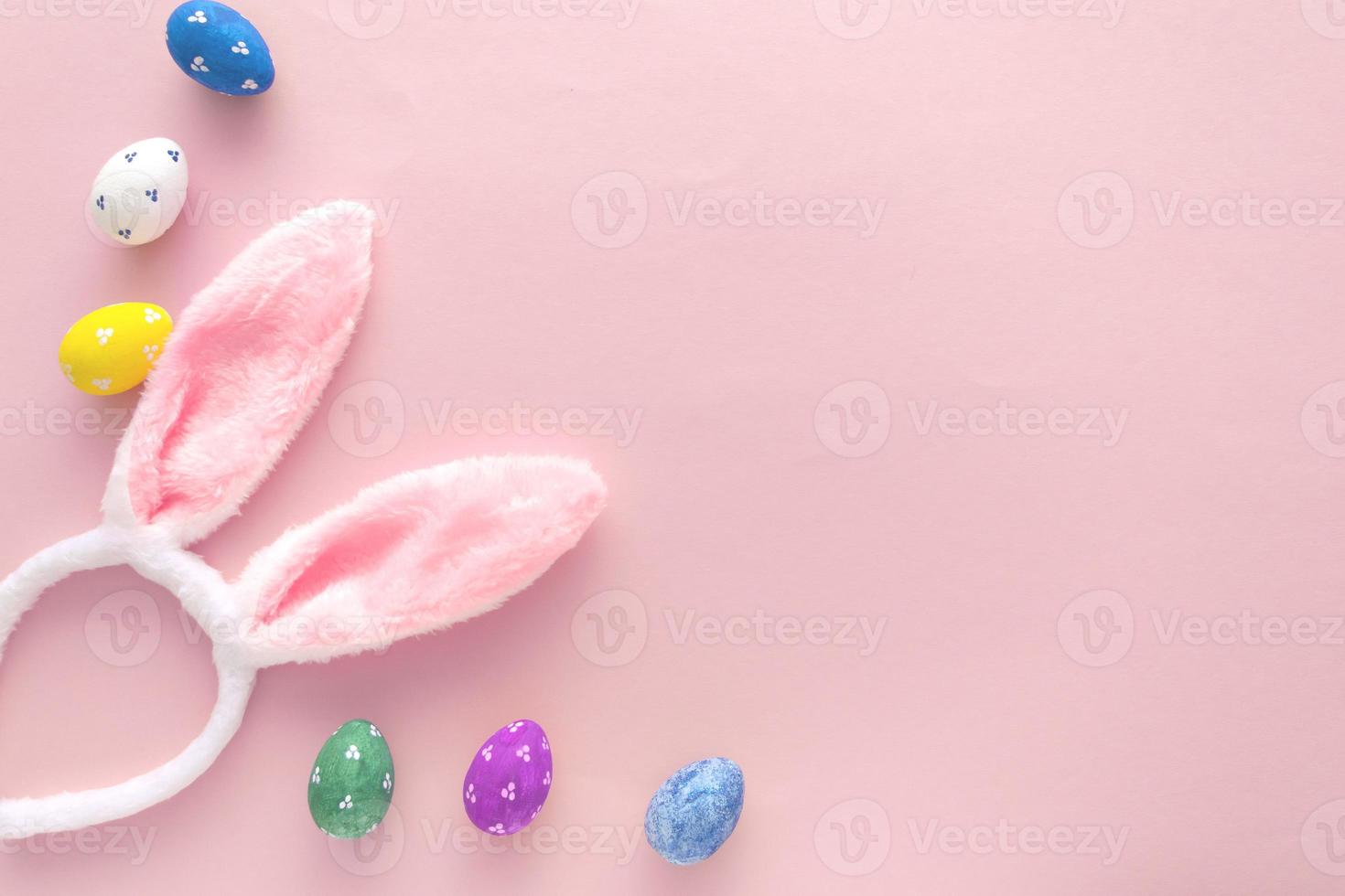 Decorated Easter eggs and bunny ears on color pink background, top view photo