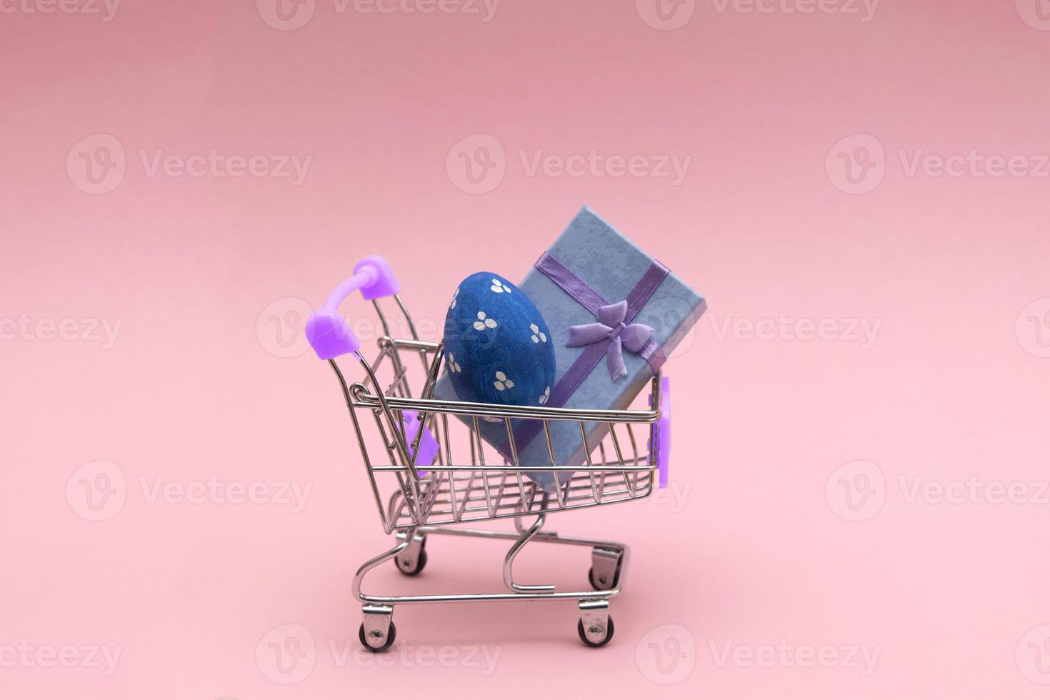 Easter eggs colorful in the shopping cart on pink background. Copy space for Text. photo