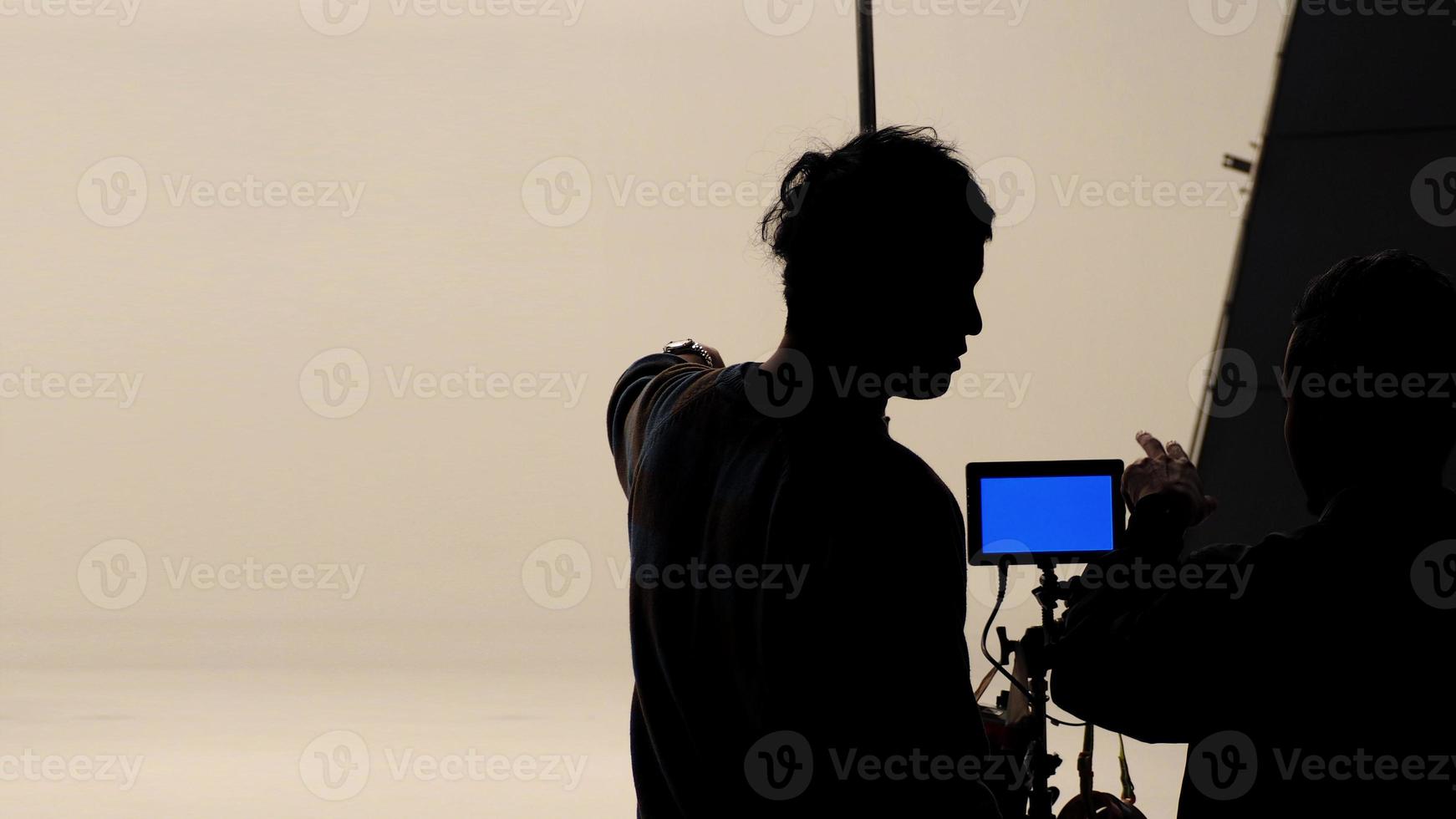 el director de cine y el fotógrafo están hablando o consultando para hacer un estudio antes de grabar video e iluminación de fondo de silueta. foto