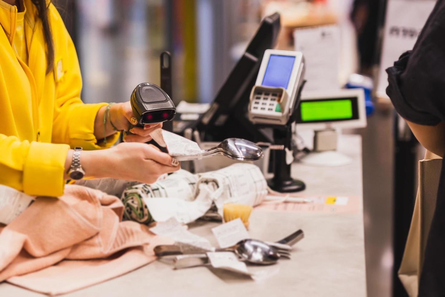 Woman cashier scanning product at checkout counter in store. photo