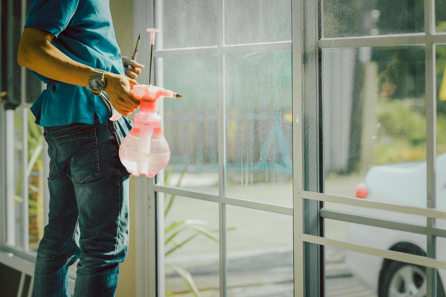Woker wrapper tinting a window using foggy spray. photo