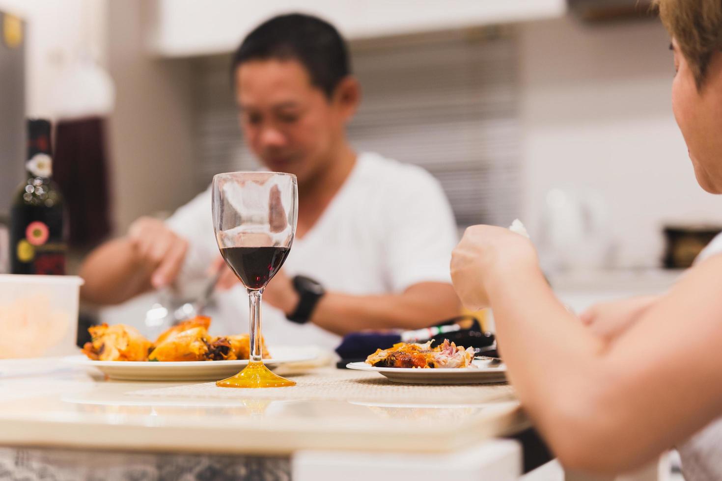 pareja cenando con copas de vino tinto en la mesa en casa. foto